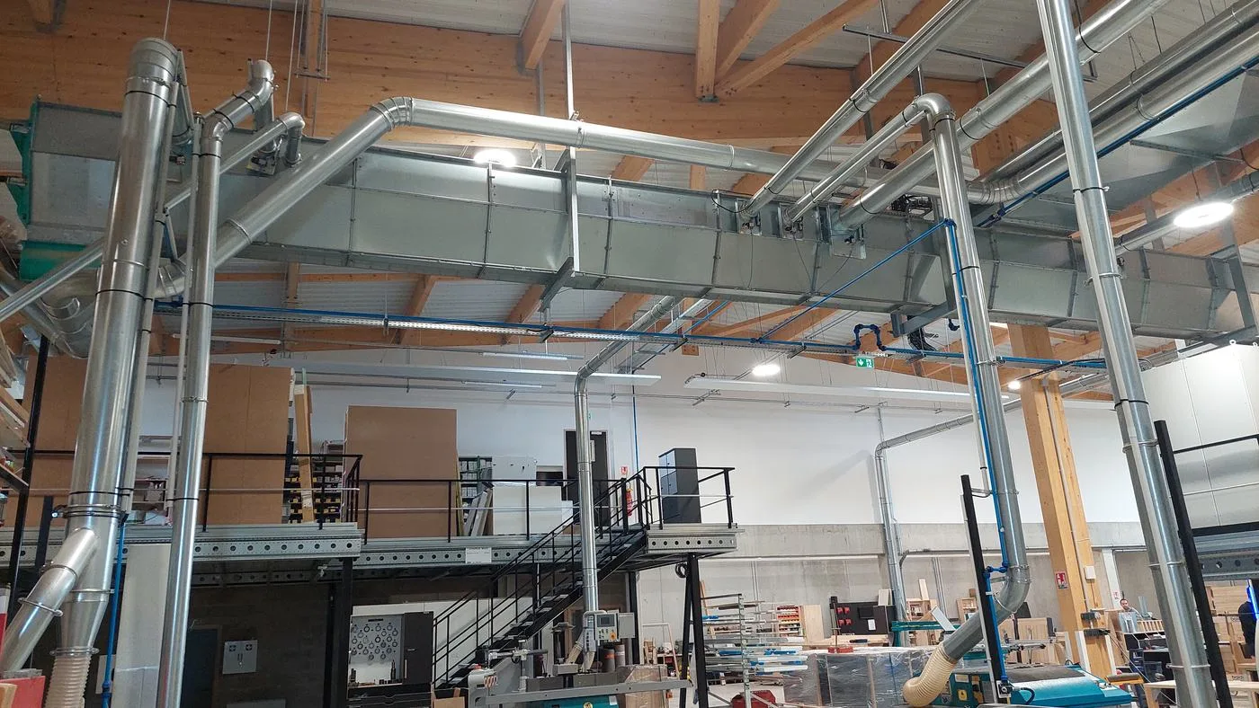 Réseau d'aspiration en acier galvanisé reliant les machines au dépoussiéreur dans un atelier bois